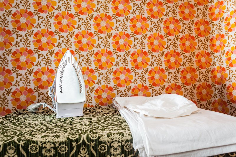 an iron appliance over a wall covered with retro styled floral wallpaper