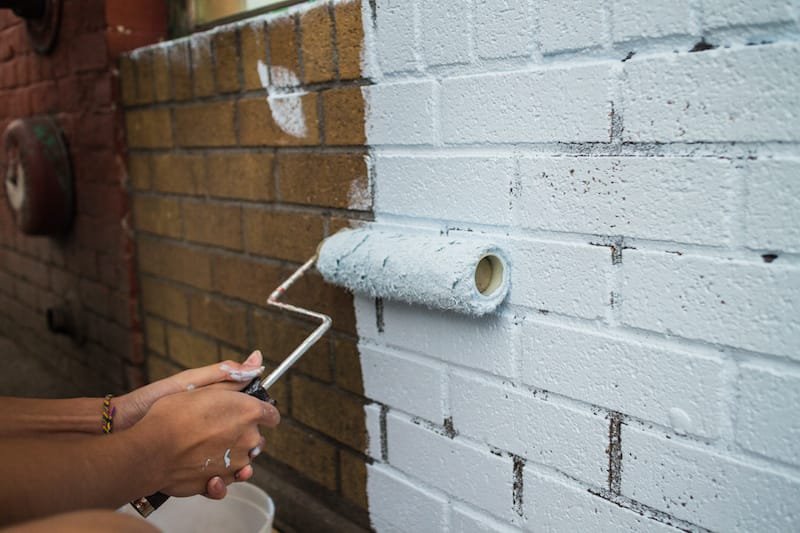 painting on a fresh coat on brick wall