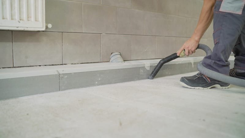 Industrial vacuum cleaner at work. A worker removes dust from a construction site with a vacuum cleaner. A man using an industrial vacuum cleaner.