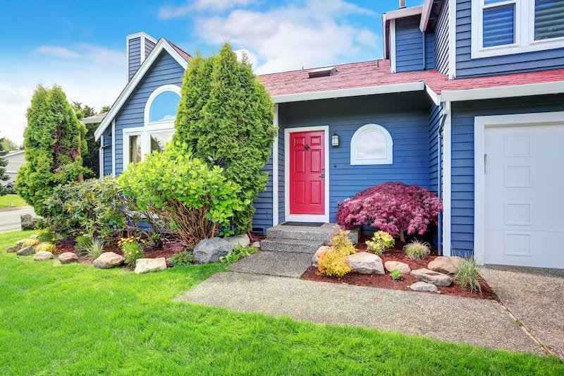 Beautiful curb appeal with blue exterior paint and red roof. Nice front landscape design.