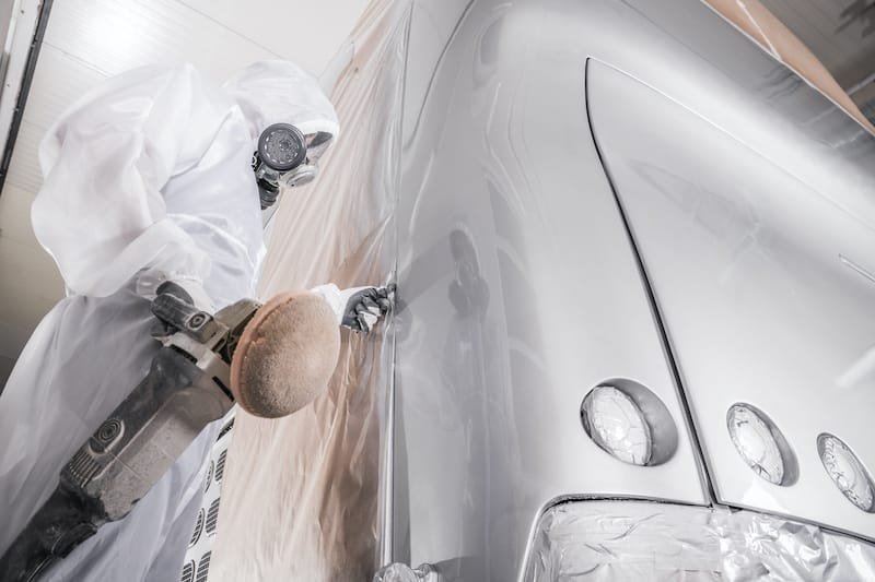 Transportation Industry. Collision Center Job. Professional Body Shop Worker Polishing Newly Painted Coach Bus Body