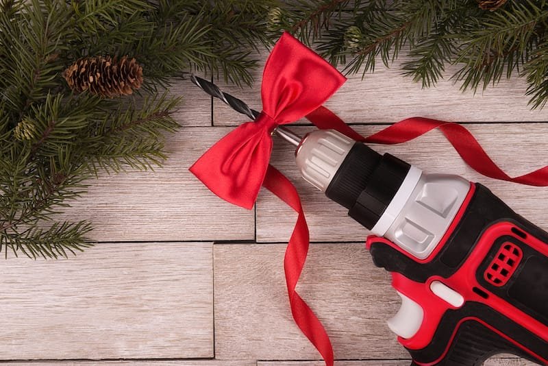 Electric drill on a white wooden plank, directly above. Copy space for your text. Offering tool in gift, concept.