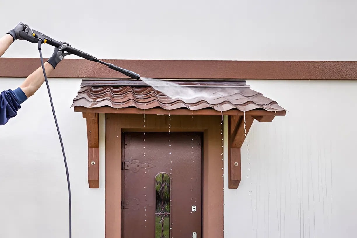 Pressure washing exterior entryway and roof surface before repainting by a painting company in Eagle, ID