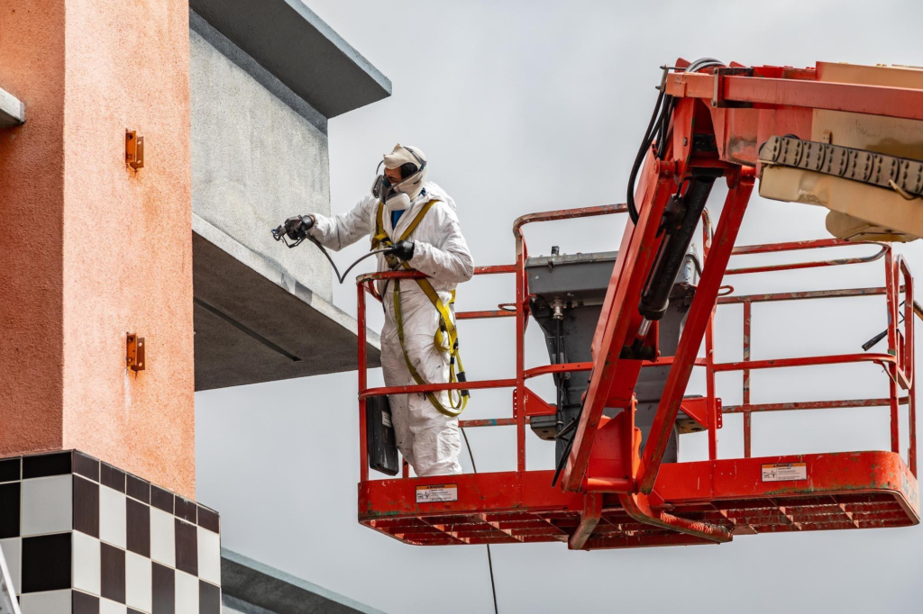 Professional commercial painter applying Tex-Cote exterior coating to a commercial building in Star, ID